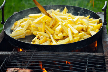 Roast potatoes in a large pan. Delicious food at the festival. Field kitchen at the hearth.