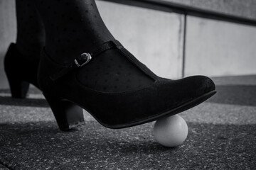 Foot of a woman poised above a whole hens egg on the ground