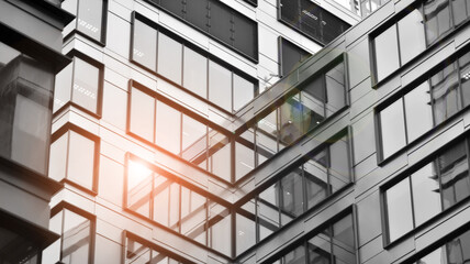 Obraz premium Modern architectural details. Modern glass facade with a geometric pattern. Contemporary corporate business architecture. Red sun on horizon. Black and white toned image.