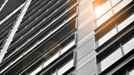 Modern architectural details. Modern glass facade with a geometric pattern. Contemporary corporate business architecture. Red sun on horizon. Black and white toned image.