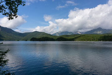 Fototapeta na wymiar Ein blauer See. Im Hintergrund sind Berge und am Himmel Wolken.