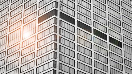 Modern architectural details. Modern glass facade with a geometric pattern. Contemporary corporate business architecture. Red sun on horizon. Black and white toned image.