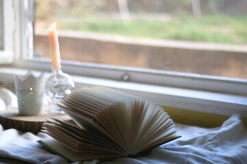 Open book and lit candles. Hygge at home. Selective focus.