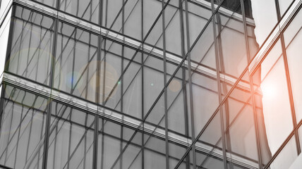 Modern architectural details. Modern glass facade with a geometric pattern. Contemporary corporate business architecture. Red sun on horizon. Black and white toned image.