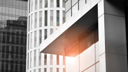 Modern architectural details. Modern glass facade with a geometric pattern. Contemporary corporate business architecture. Red sun on horizon. Black and white toned image.