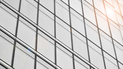 Modern architectural details. Modern glass facade with a geometric pattern. Contemporary corporate business architecture. Red sun on horizon. Black and white toned image.
