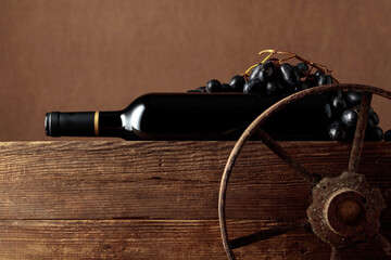 Old wooden cart with bottle of red wine and grapes.
