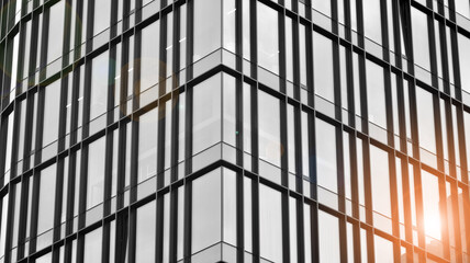 Fototapeta premium Modern architectural details. Modern glass facade with a geometric pattern. Contemporary corporate business architecture. Red sun on horizon. Black and white toned image.