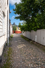 A view of an alley with old stone pavement during sunny summer day.