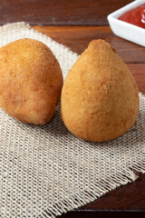Tasting traditional coxinha of chicken with ketchup.