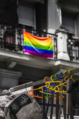 Fototapeta na wymiar LGTBI+ pride flag in the background and hangers with the same colors in the street