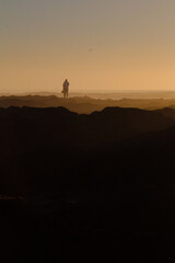 A hazy sunset on the rocks of a distant coast