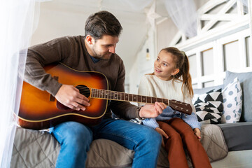 Smiling happy father with child having fun and playing guitar at home