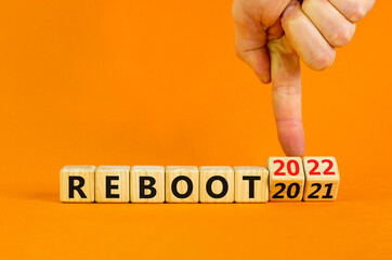 2022 reboot new year symbol. Businessman turns wooden cubes and changes words 'Reboot 2021' to...