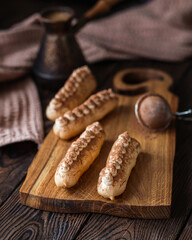 French dessert. Coffee eclairs on a brown background. Sweet French food. Home bakery. Eclair on a wooden board.