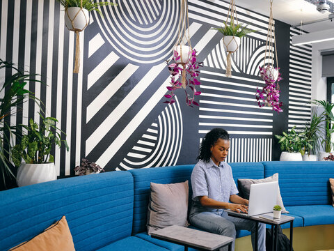 Woman Using Laptop In Office Lounge Area