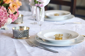 A table meal decoration with white plate and spoon, glasses of champagne and beautiful fresh flower with festive and celebrate atmosphere