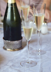 A tall glasses of cool and fresh champagne on table with its bottle in background and celebration atmosphere 