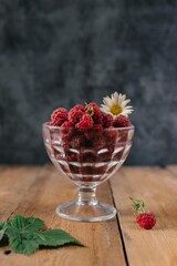 Fresh raspberries in glass vase on wooden background Flatlay