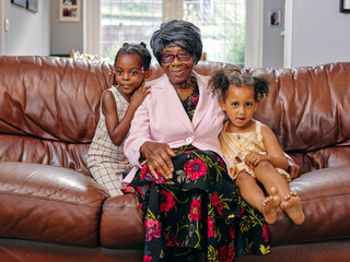 Great grandmother sitting on sofa with great granddaughters