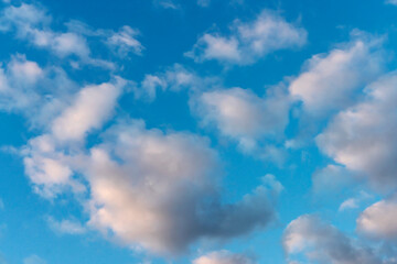 Blue sky with many small cumulus clouds illuminated by the sun as a natural background