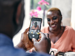UK, Close-up of man photographing woman at hotel table