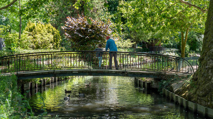 Man from behind and his little son, admiring the scenery on a bridge, overlooking the river