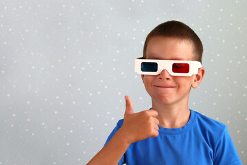 A boy in 3D movie glasses smiles on a blue background