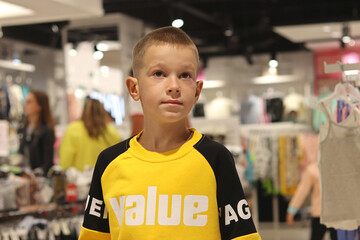 A boy in a store in a yellow jacket with the inscription VALUE