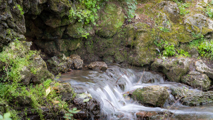 Water flowing along the stones covered with moss in the middle of nature, in spring	