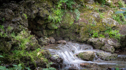 Water flowing along the stones covered with moss in the middle of nature, in spring	