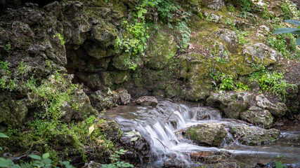 Water flowing along the stones covered with moss in the middle of nature, in spring	