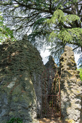 Red metal gate, arched top, between the rocks, closing the access to a waterfall