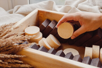 Hand take homemade soap from wooden box full of natural solid shmpoo and soaps