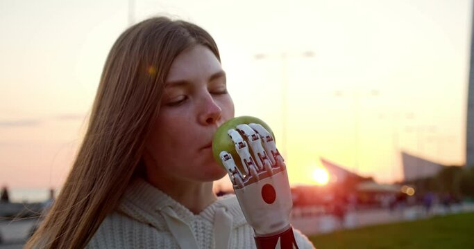a young disabled woman with a bionic arm eats an apple at sunset. the use of a robotic arm in everyday life. a happy girl with a prosthetic arm and a bioelectric artificial hand
