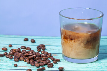 milk pour in glass of iced coffee on blue background