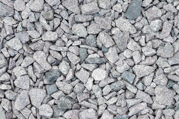 Background of natural grey granite crushed stone, macadam. Macro photo of texture of broken stone or rubble with place for text. Crushed rock. Construction Materials. Textures.