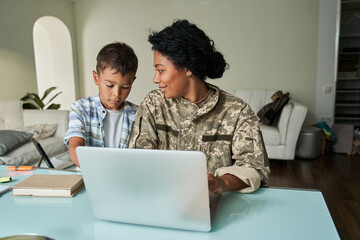 Black mother and son using laptop at table