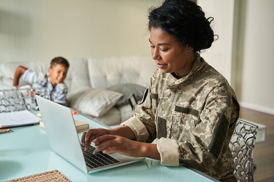 Black woman soldier using laptop at home