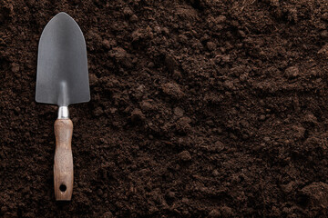 Garden trowel on soil background, close up view