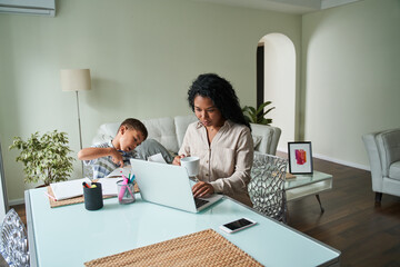 Obraz premium Black mother using laptop and child crafting