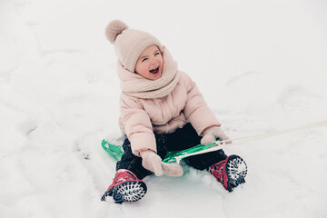 Portrait of a girl playing in the snow during a winter walk and playing snowballs, rolling and skating in the snow