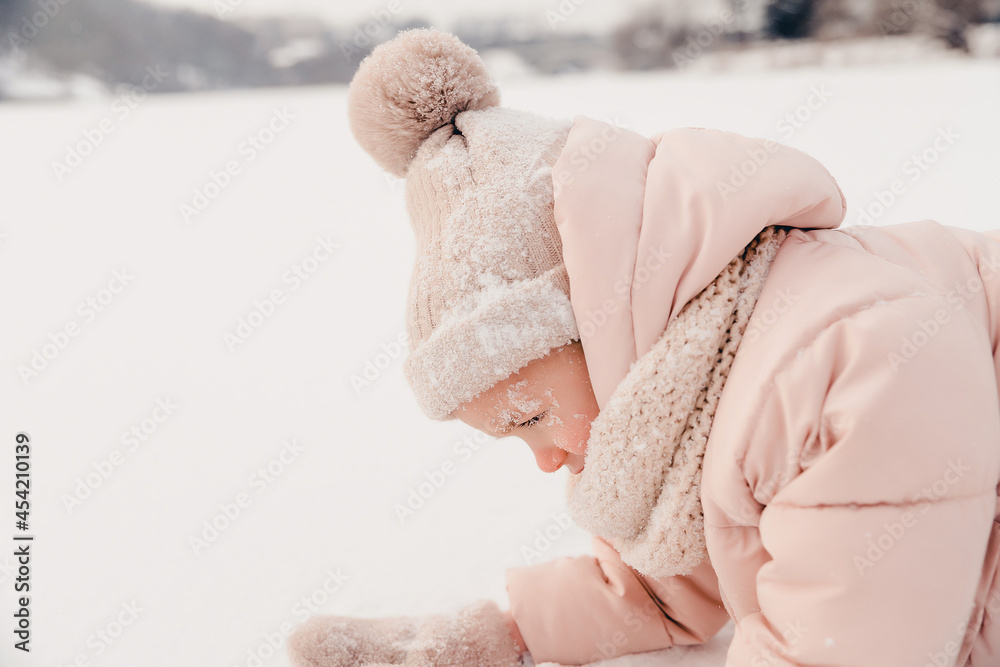 Canvas Prints Portrait of a girl playing in the snow during a winter walk and playing snowballs, rolling and skating in the snow