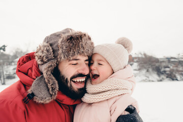 Happy loving family! Father and his baby are playing and hugging outdoors. Little child and daddy on a snowy winter walk in nature. Concept of the first long-awaited winter snowfall. copy space