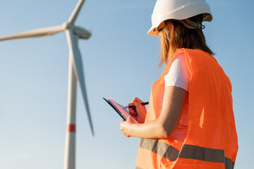 Female maintenance engineer controls the work of wind turbines and windmills. Renewable energy...