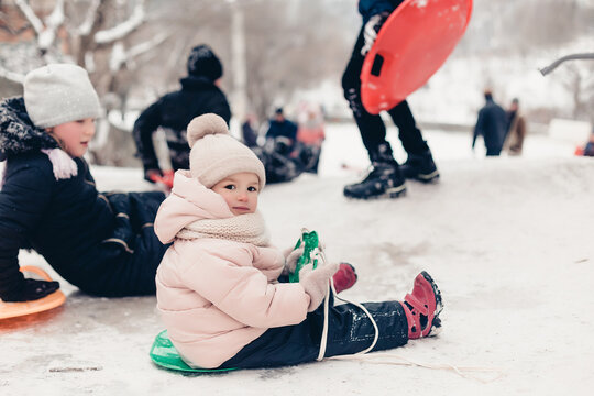 23.11.2018 Vinnitsa, Ukraine: little girl rides on an ice slide next to older children in the ordinary yard of high-rise buildings in the city where children spend winter fun