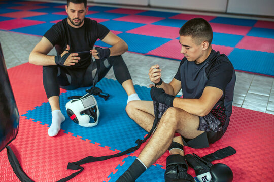 Young man preparing for exercising with boxing gloves in the gym.