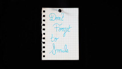 Hand written message on a ripped notebook sheet, "Don't forget to smile"
