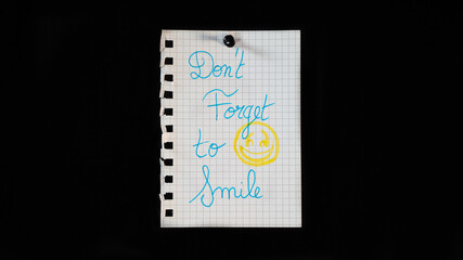 Hand written message on a ripped notebook sheet, "Don't forget to smile"
