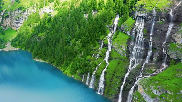 Aerial look-down view of a beautiful waterfall falling into a mountain lake with turquoise water